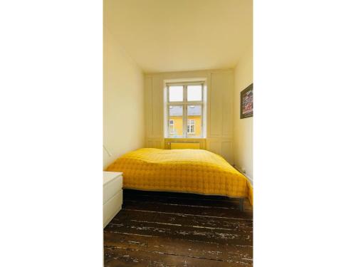 a bedroom with a yellow bed and a window at ApartmentInCopenhagen Apartment 664 in Copenhagen