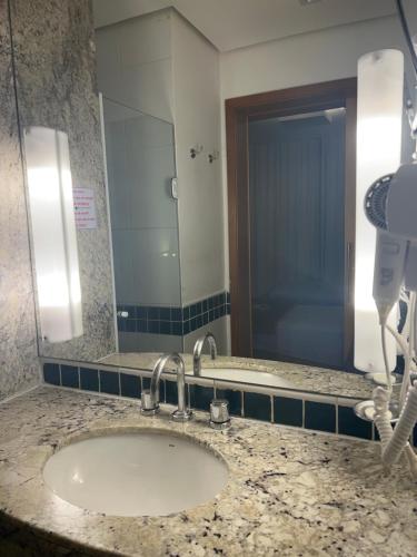 um balcão de casa de banho com um lavatório e um espelho em Flat Ibirapuera Jardins SP com garagem inclusa! em São Paulo