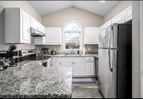 a kitchen with white cabinets and a black refrigerator at Beautiful home in Rocky Mount