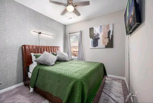 a bedroom with a green bed with a ceiling fan at Beautiful home in Rocky Mount