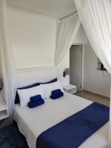 a bedroom with a white bed with two blue pillows at Serenity Nhabanga, Bilene in Bilene