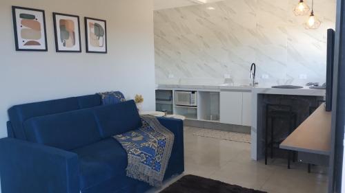 a living room with a blue couch and a kitchen at Apê Bella Vista Campos in Campos do Jordão