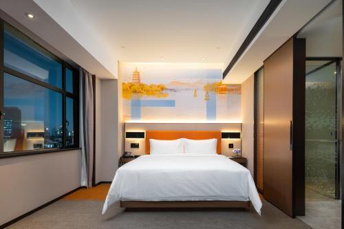 um quarto com uma cama e uma grande janela em Hampton by Hilton Hangzhou West Lake em Hangzhou