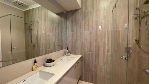 a bathroom with a shower and a sink and a mirror at Brand new house near Box Hill in Nunawading