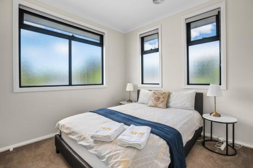 a white bedroom with a bed and two windows at Brand new house near Box Hill in Nunawading