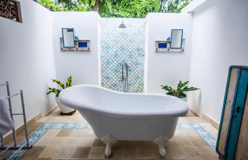 a white bath tub in a bathroom with mirrors at Lata Lama in Lovina