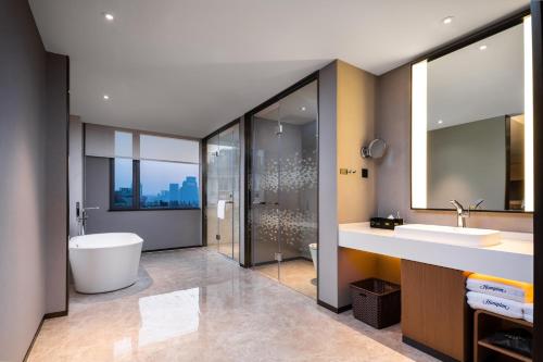 ein Badezimmer mit zwei Waschbecken, einer Badewanne und einer Dusche in der Unterkunft Hampton by Hilton Hangzhou West Lake in Hangzhou