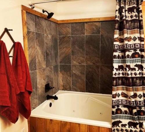 a bathroom with a tub and a shower curtain at The Hideaway at Bear Mountain Log Cabins in Eureka Springs