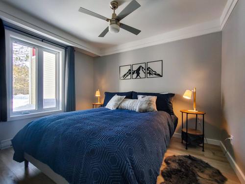 Chalet Détente Orford في Orford: غرفة نوم بسرير ازرق ومروحة سقف