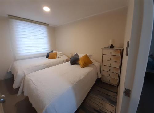 a bedroom with two beds and a dresser and a window at Chillan Centro in Chillán