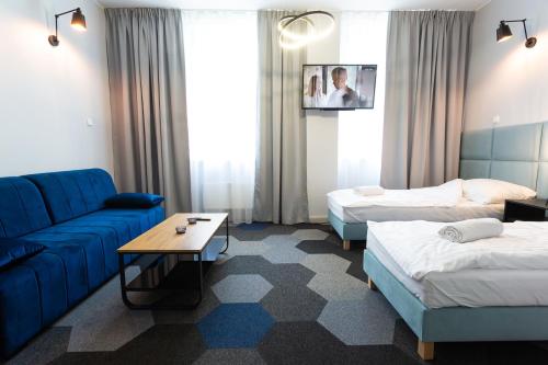 a hotel room with two beds and a blue couch at Moon Apartments Gdańsk in Gdańsk