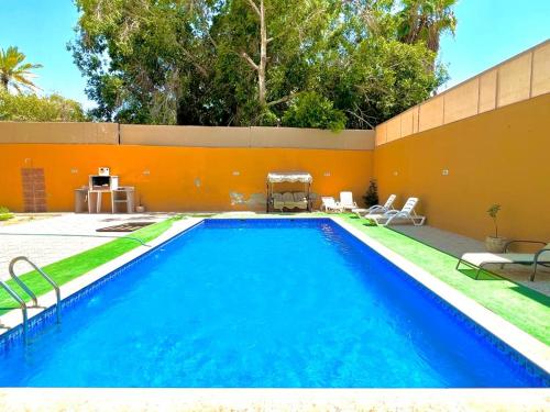 a swimming pool in a backyard with an orange wall at Al Andalus Chalets ‏ in Shūnat Nimrīn