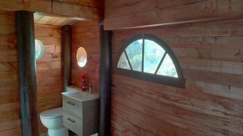 a bathroom with a toilet and a window at Rivendell Farmstay Hobbit Hole in Cambridge