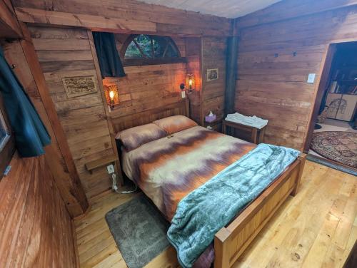 a bedroom with a bed in a room with wooden walls at Rivendell Farmstay Hobbit Hole in Cambridge