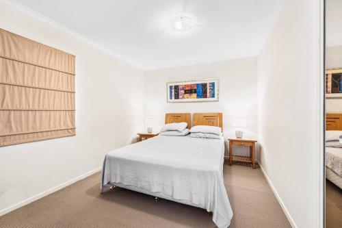 a white bedroom with a bed and two windows at Modern comfort Chippen119 Self Catering in Sydney