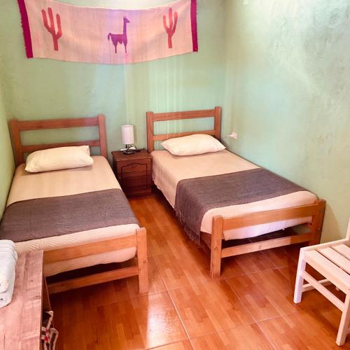 a room with two beds and a table and a chair at Casa TAQI in San Pedro de Atacama