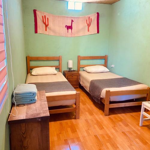 Habitación con 2 camas y una bandera en la pared en Casa TAQI, en San Pedro de Atacama