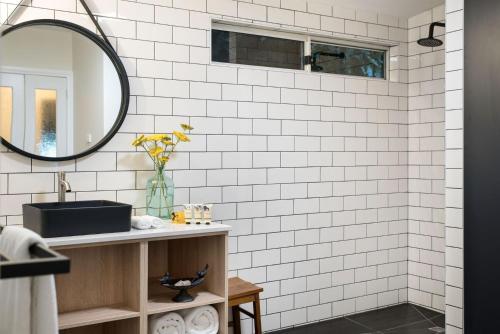 uma casa de banho com azulejos brancos do metro e um espelho em Botanica em Daylesford