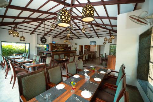 een eetkamer met houten tafels en stoelen bij The Ocean Pearl Resort And Spa in Hubli