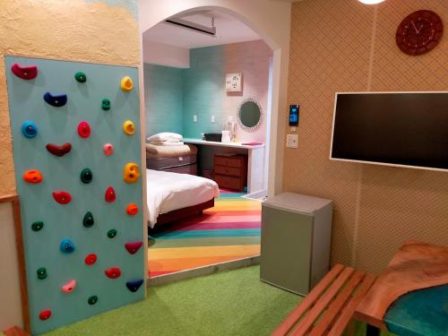 a room with a bedroom with a climbing wall and a tv at Buzz Resort in Onna