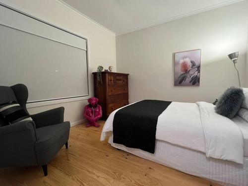 a bedroom with a large bed and a chair at The Cottage in Queanbeyan