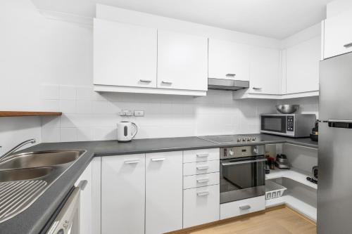 a kitchen with white cabinets and stainless steel appliances at Cleveland 49 Self Catering in Sydney
