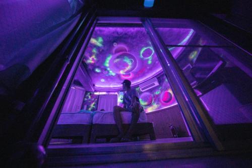 a person sitting on a bus in a purple room at Buzz Resort in Onna