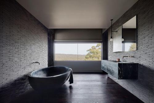 a bathroom with a large tub and a large window at Breakneck Gorge Oikos in Hepburn Springs