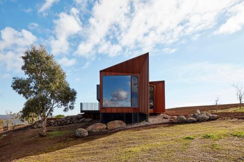 a small house on a hill with a large window at Breakneck Gorge Oikos in Hepburn Springs