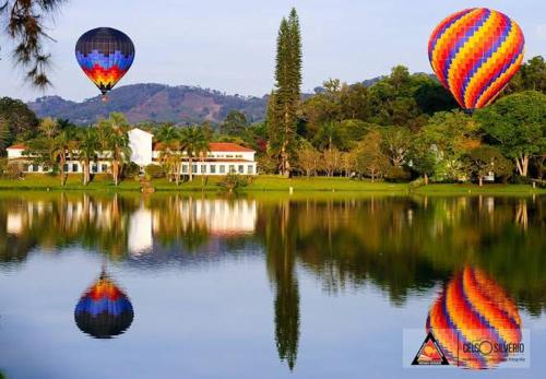 two hot air balloons flying over a body of water at Apartamento em São Lourenço-mg in São Lourenço