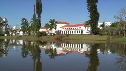 a large white building next to a large lake at Apartamento em São Lourenço-mg in São Lourenço