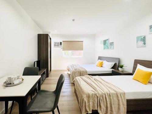 Habitación de hotel con 2 camas, mesa y sillas en Furnished Rentals at Mangrove Residences Mactan, en Punta Engaño