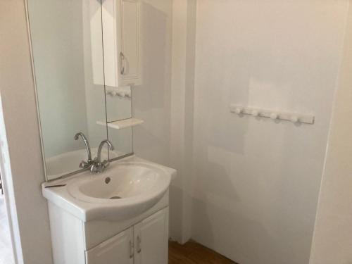 a white bathroom with a sink and a mirror at bungalow les cases près de la Mare à joncs in Cilaos