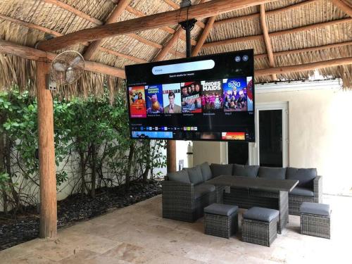a large screen in a pavilion with a couch and a tv at Villa Palma-Hollywood Beach-Private Pool & Beachwalk! in Hollywood