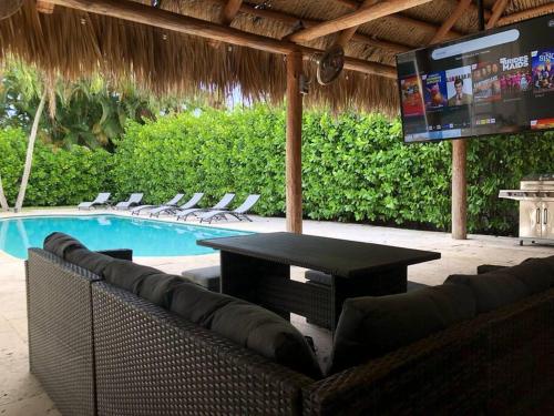 a patio with a table and a tv and a pool at Villa Palma-Hollywood Beach - Winter & Spring Break Getaway! in Hollywood