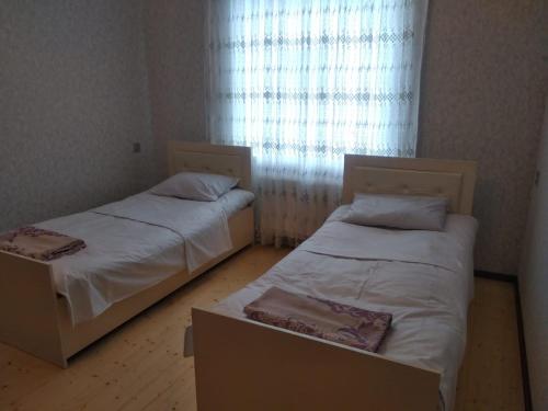 two beds in a small room with a window at Elchins villa in Gabala