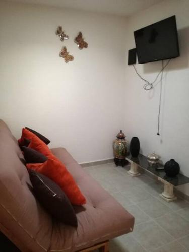 ein Wohnzimmer mit einem Sofa mit Kissen und einem TV in der Unterkunft Visita lo mejor de Querétaro in Pedro Escobedo
