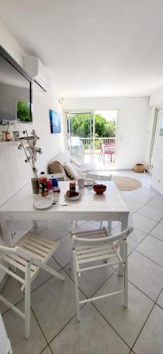 une table blanche et des chaises dans un salon dans l'établissement Terrasses 1 sur le Port de Plaisance, au Grau-du-Roi
