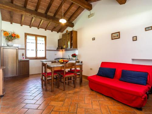 uma sala de estar com um sofá vermelho e uma mesa em Spacious Farmhouse in Castiglion Fiorentino with Garden em Castiglion Fiorentino