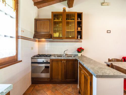 uma cozinha com armários de madeira e um forno com placa de fogão em Spacious Farmhouse in Castiglion Fiorentino with Garden em Castiglion Fiorentino