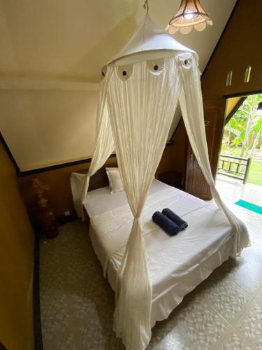 a bedroom with a white bed with a canopy at MATRAHAYA BUNGALOWS in Tetebatu