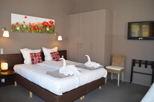 two swans sitting on a bed in a room at Hotel Ambrosia in Ypres