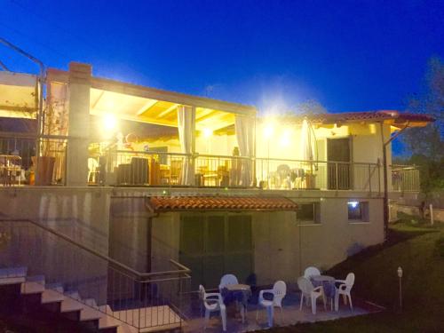a house with chairs and a balcony at night at B&B Oasi Vetoio in LʼAquila