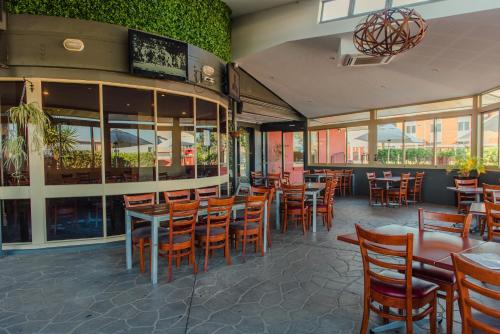 a restaurant with wooden chairs and tables and windows at Northside Hotel Albury in Lavington