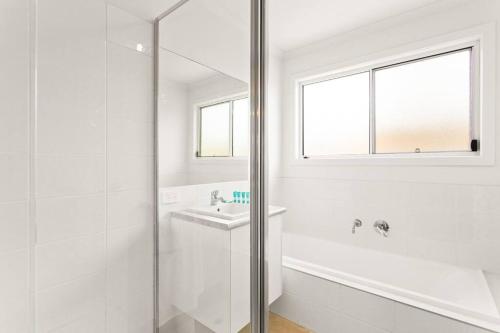 a white bathroom with a shower and a sink at Cozy Beach Bungalow in Cowes in Cowes