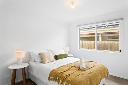 a white bedroom with a bed and a window at Cozy Beach Bungalow in Cowes in Cowes