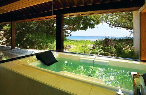 a bath tub with a view of the ocean at Hyakunagaran in Nanjo