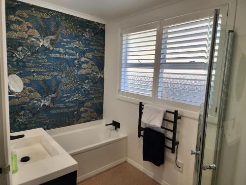 a bathroom with a tub and a sink and a window at Roslyn Sanctuary Hereford St Dunedin in Dunedin