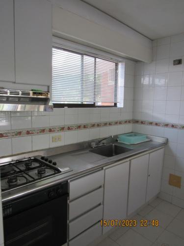 a kitchen with a sink and a stove and a window at Apartamento Girardot Resort in Girardot