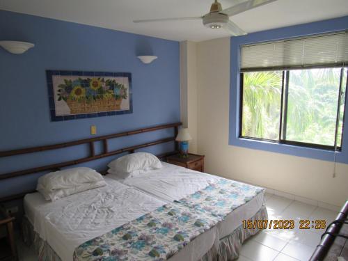 a bedroom with a bed with blue walls and a window at Apartamento Girardot Resort in Girardot